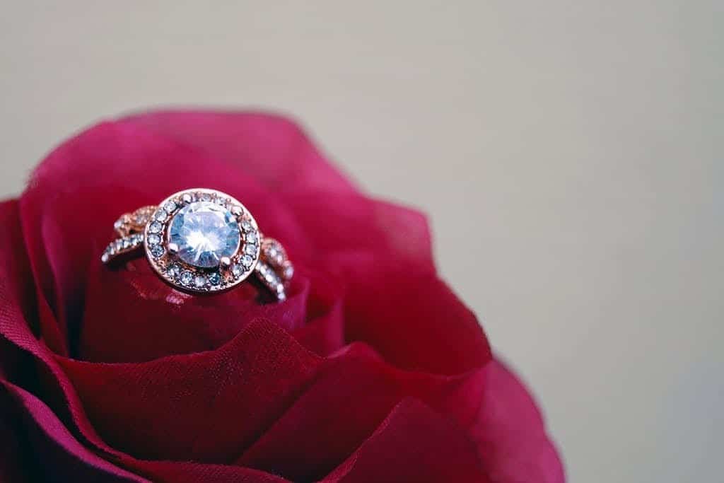Closeup Photography of Clear Jeweled Gold-colored Cluster Ring on Red Rose