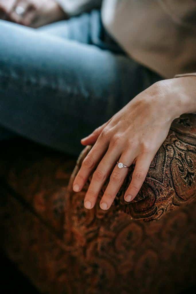 Woman with ring on finger of hand sitting on couch