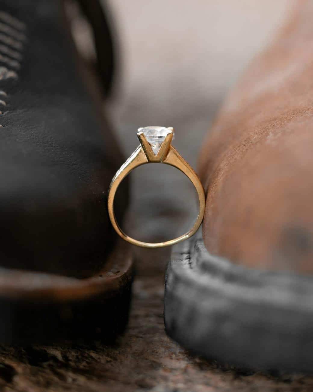 close up of an engagement ring stuck between two boots