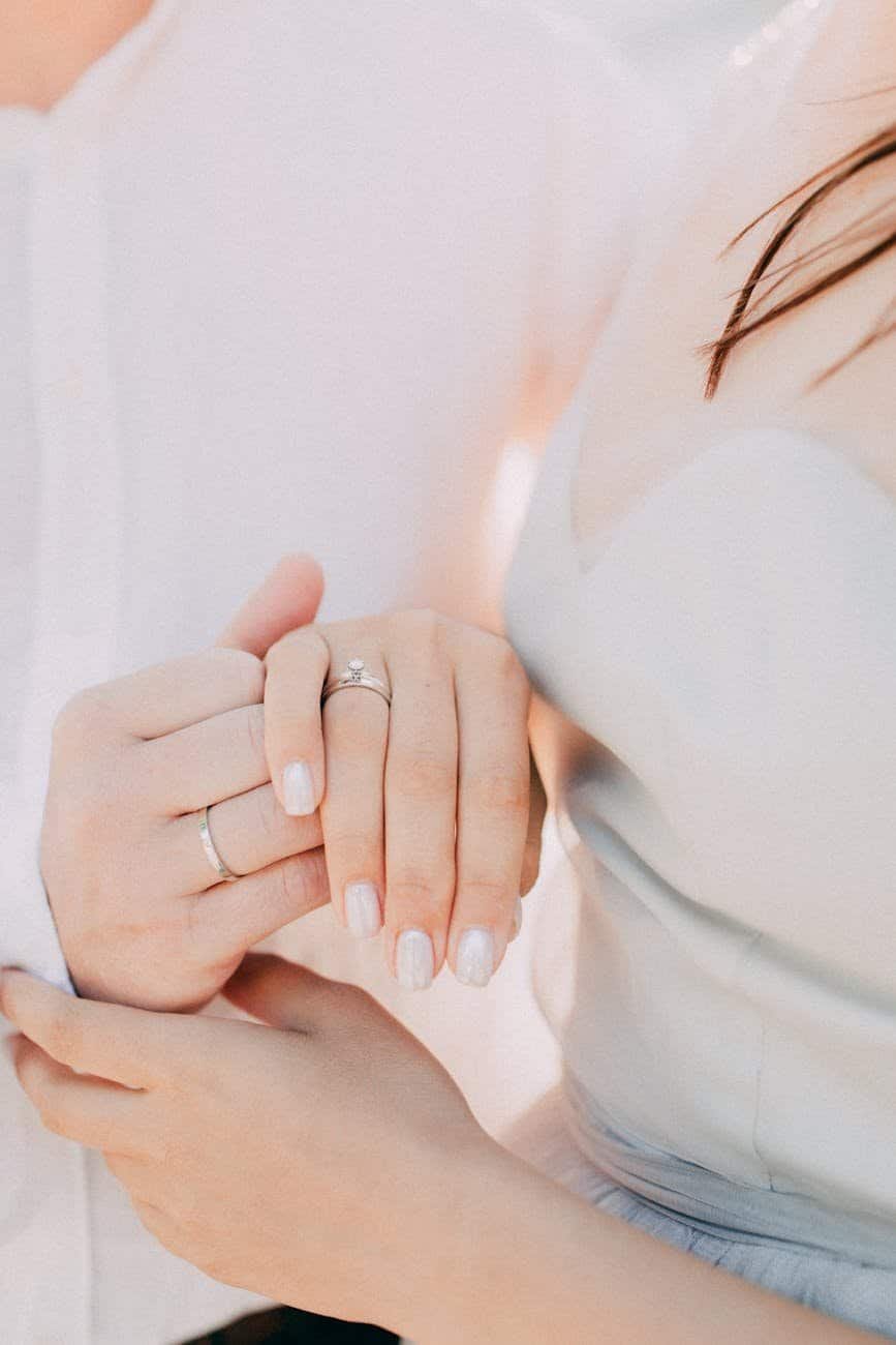 couple holding hands wearing engagement rings